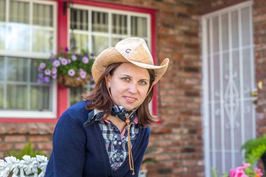 Country style portrait of a beautiful brunette young woman wearing a cowboy hat