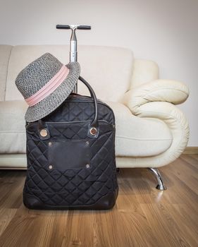 Suitcase and straw hat ready for travelling