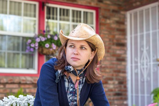 Country style portrait of a beautiful brunette young woman wearing a cowboy hat