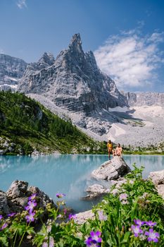 Morning with clear sky on Lago di Sorapis in the Italian Dolomites, milky blue lake Lago di Sorapis, Lake Sorapis, Dolomites, Italy. Couple man and woman mid age walking by the lake in the mountains 