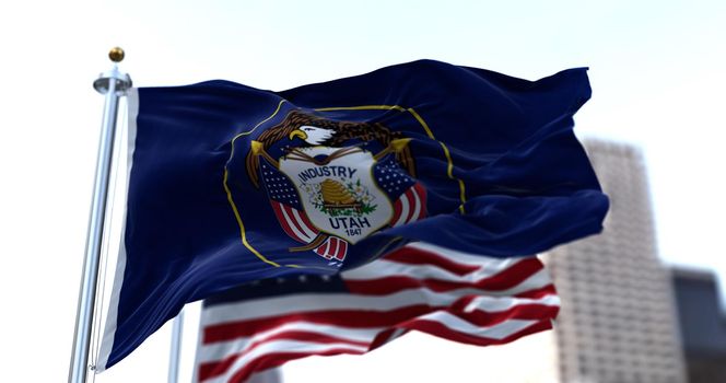 the flag of the US state of Utah waving in the wind with the American stars and stripes flag blurred in the background. Utah was it admitted in 1896 as the 45th of the Union. Independence and unity