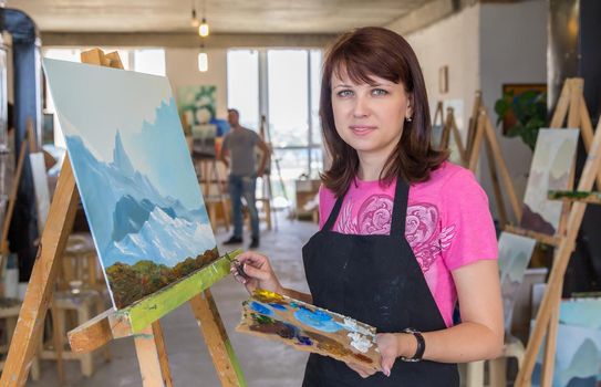 Young woman painting mountains in art studio