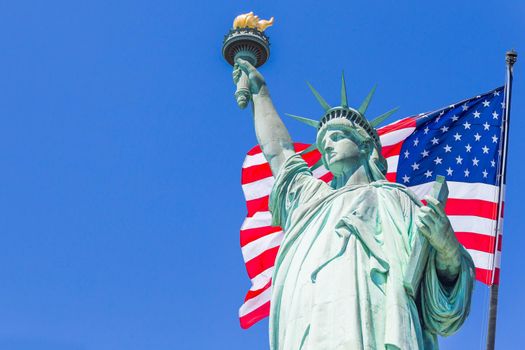 Statue of Liberty with large american flag in the background.