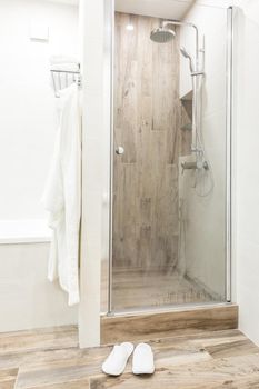 Walk in shower in bathroom with wooden style tile, glass door and hanging bathrobe