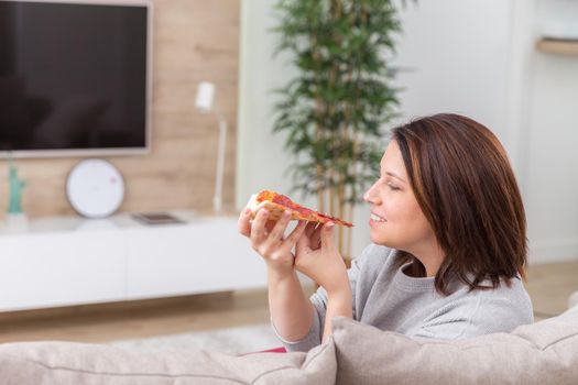 Girl eating pizza and watching tv