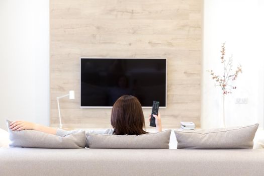 Young woman watching TV in the living room. black screen with copy space