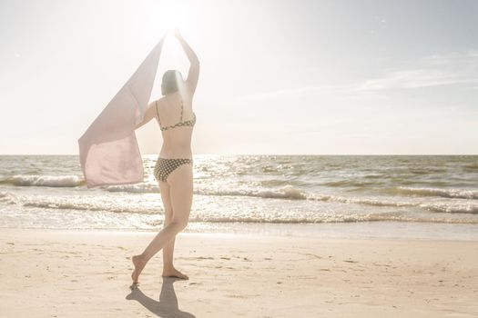 Woman standing with towel on the beach with ocean