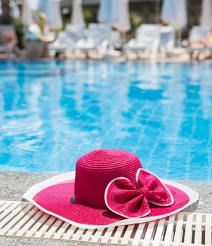 Nice pink hat with a bow near the pool