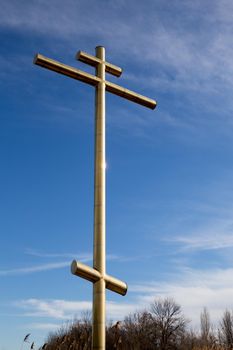 Big golden cross on a roadside with blue sky