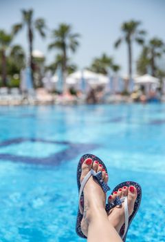 Woman wearing flip-flops laying on the sunbed near the pool