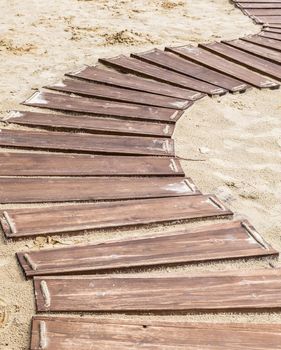 Wooden beach boardwalk, path with sand with copy space