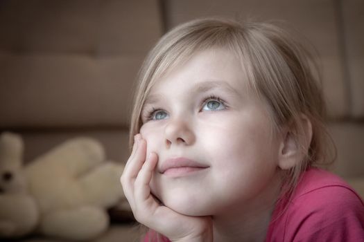 Sad little girl feels lonely laying on a floor and thinking