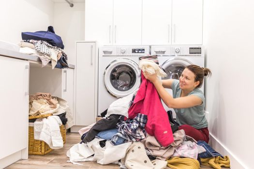 Happy woman in laundry room with a pile of dirty clothes