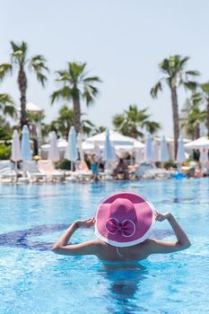 Woman in pink hat standing in a pool