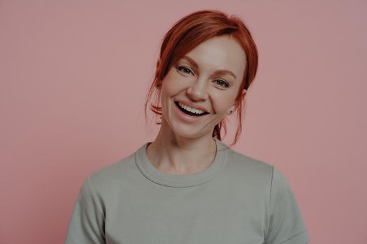 Young charming smiling redhead woman in casual clothes posing isolated on pink background in studio, gorgeous redhead female feeling happy, enjoying life, looking at camera with bright smile