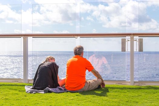 Couple sitting on real grass lawn on cruise ship