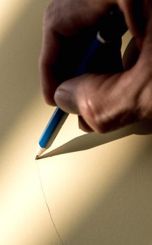 Human's hand holding pencil to write on the paper in shadow