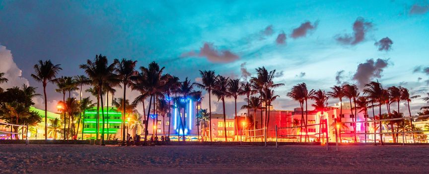 Miami Beach Ocean Drive hotels and restaurants at sunset. City skyline with palm trees at night. Art deco nightlife on the South beach