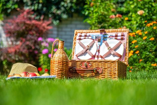 Picnic basket with food on green sunny lawn