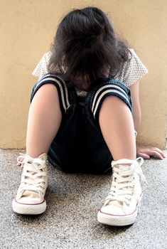 A Lonely girl sitting behind the concrete wall