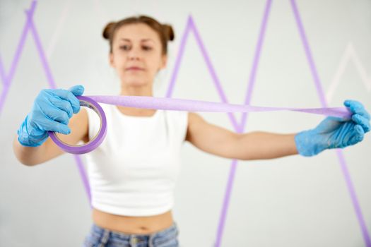 Young woman playing with masking tape before painting the walls