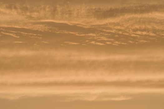 Abstract sky background of deep golden sunset clouds. Full frame color and texture, copy space possible throughout. Rich tones and varied clouds.