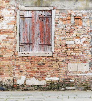 Old brick wall with closed vintage wooden window