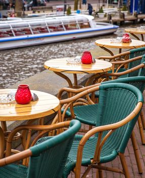 Street cafe with boat on background in Amsterdam, Netherlands