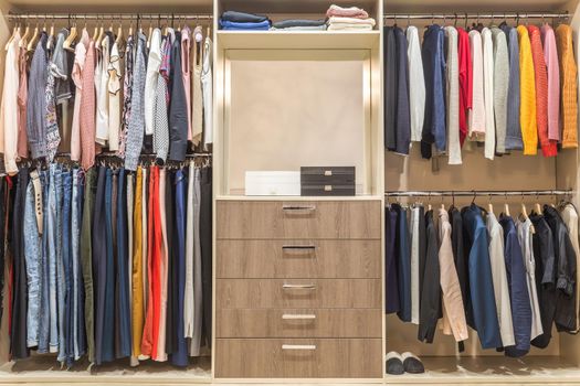 Modern wooden wardrobe with clothes hanging on rail in walk in closet design interior
