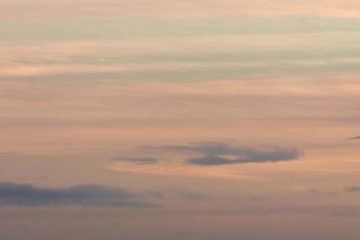 Plain pastel color themed background, made by a sky of gentle clouds at sunset. Mainly orange with some blue, very calm and wispy. Lots of copy space