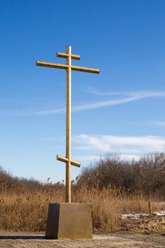 Big golden cross on a roadside with blue sky