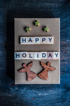 Holiday card concept with wooden blocks with letters on gift box on wooden background