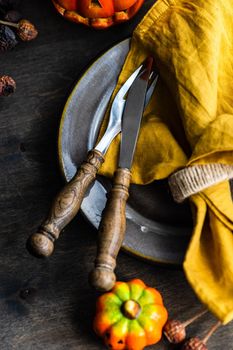 Thanksgiving holiday table setting with pumpkin and dried leaves