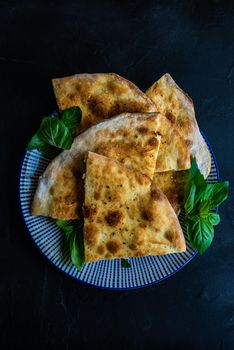 Homemade pizza with basil leaves on the dark table