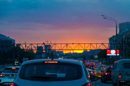 Traffic jam on the road in the evening at sunset in summer. Red lights from headlights.