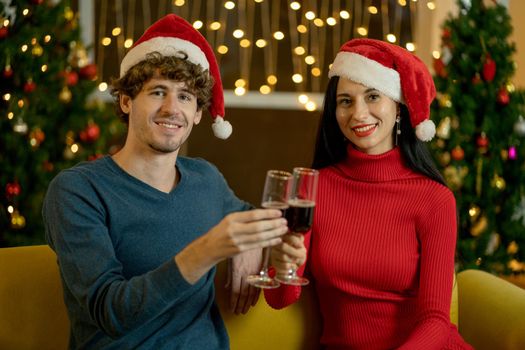 Caucasian couple man and woman hold glass of wine and celebrate together in Christmas festival at night.