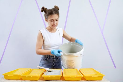 Young woman pouring paint into paint tray. Diy concept