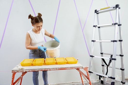 Young woman pouring paint into paint tray. Diy concept