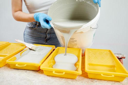 Young woman pouring paint into paint tray. Diy concept