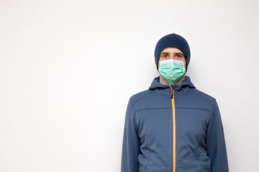 Man with green protective mask on white background. A man with a blue jacket, with a hood.