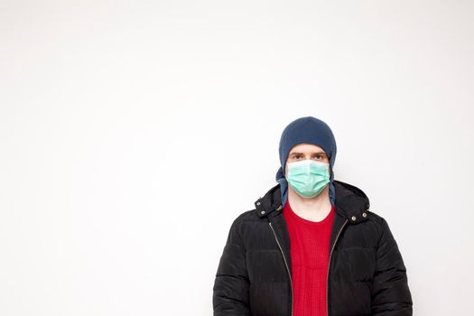 Man with green protective mask on white background. A man with a red sweater and a black jacket.