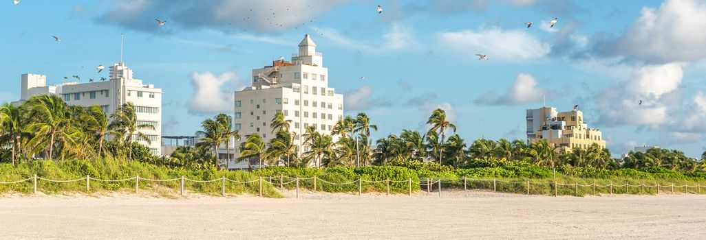 Art deco district of South Beach Miami. The buildings are painted in pastel colors surrounded by tropical palm trees.