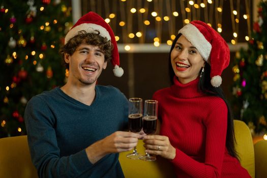 Couple lover man and woman smile to camera with hold glass of  champagne or wine to celebrate Christmas festival together at night.