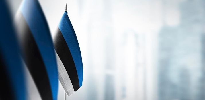 Small flags of Estonia on a blurry background of the city.