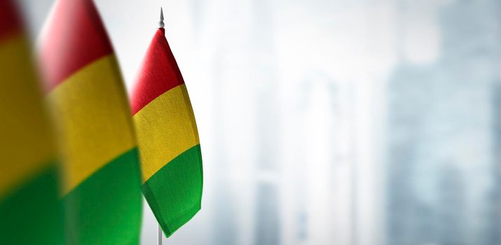 Small flags of Guinea on a blurry background of the city.