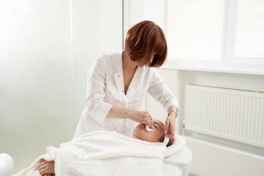 Doctor puts needles into female face on the acupuncture therapy in beauty salon. Alternative Medicine concept