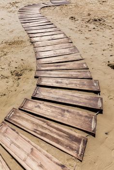 Wooden beach boardwalk, path with sand with copy space