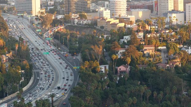 Busy rush hour intercity highway in metropolis, Los Angeles, California USA. Urban traffic jam on road in sunlight. Aerial view of cars on multiple lane driveway. Freeway with automobiles in LA city.
