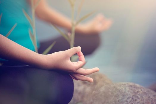 Close up of a women hands doing yoga exercise in the river background.