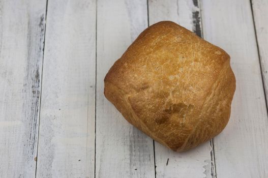 Bread, freshly baked at home, placed on a white wooden board